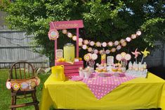 a yellow table topped with cupcakes and lemonade