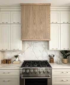 a stove top oven sitting inside of a kitchen next to white cupboards and drawers