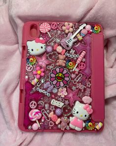 a pink case with hello kitty and other items on top of it, sitting on a pink blanket