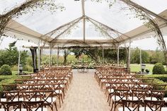 an outdoor wedding venue with wooden chairs and tables set up under a tented area