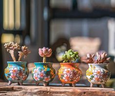 three small pots with flowers painted on them