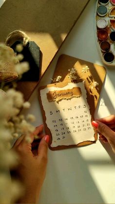 two hands holding a calendar on top of a table