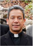 a man wearing a priest's outfit and standing in front of some rocks