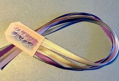 a purple and gold ribbon with a tag on it