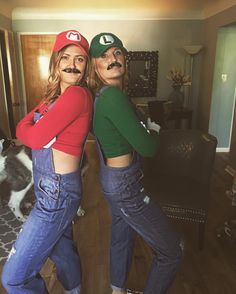 two women dressed up as mario and luigi from mario bros posing in front of a cat