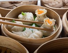 several wooden bowls filled with dumplings and chopsticks on top of each other