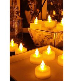 many lit candles sit in front of a mirror