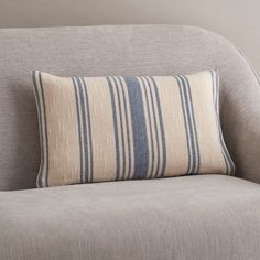 a gray couch with a blue and white striped pillow on top of it's back