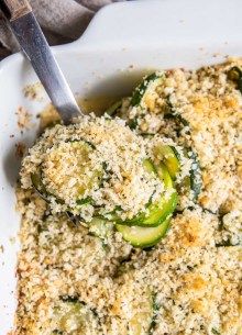 a white dish filled with cooked vegetables covered in parmesan cheese and breadcrumbs