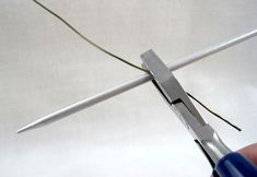 a pair of scissors being used to cut the wire on top of a piece of metal