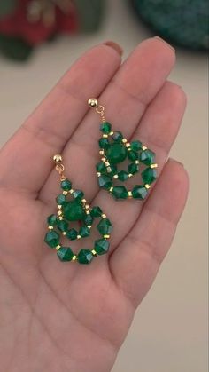 a pair of green and gold earrings in someone's hand