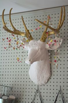 a deer head with gold antlers hanging on the wall next to a polka dot wallpaper