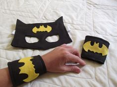 a person wearing a batman mask and wristbands on top of a white bed