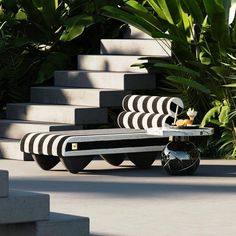 a black and white bench sitting on top of cement steps next to some plants in the background