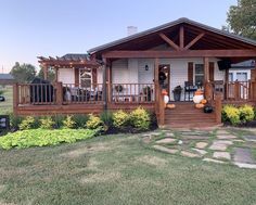 a small house with porches and lights on it's front porch, surrounded by green grass