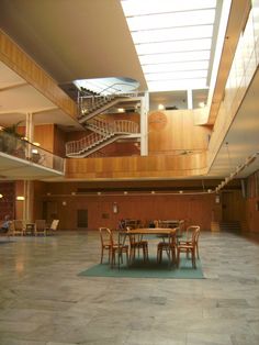 an empty room with tables and chairs in the center, stairs up to the second floor