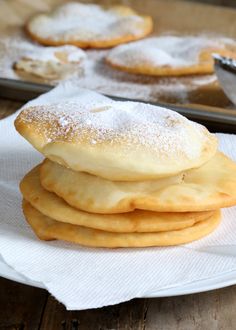 a stack of pancakes sitting on top of a white paper towel covered in powdered sugar