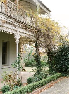 an old white house with ivy growing on it's sides and the front porch