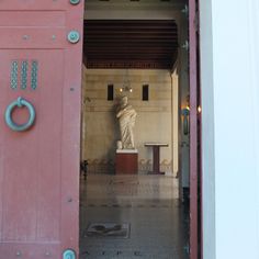 an open door with a statue in the background