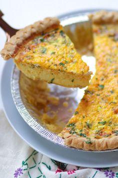 a quiche is being lifted from a pie dish with a wooden spoon in it