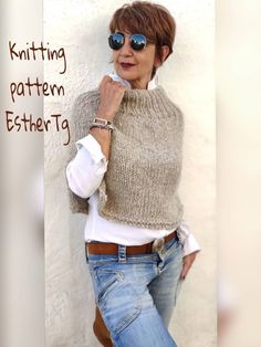 the woman is wearing a knitted sweater and jeans with her hand on her hip