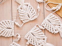 four white macrame ornaments with tassels on top of a wooden table