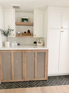 a kitchen with white cabinets and wood flooring in the center is an open shelving unit