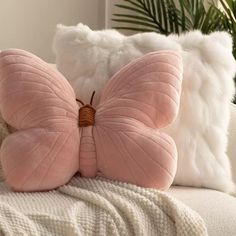 a pink butterfly pillow sitting on top of a white couch