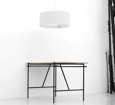 a black and white photo of a table with a light hanging from it's side