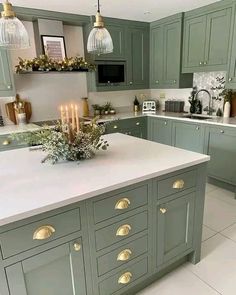 a kitchen filled with lots of green cabinets and white counter tops covered in candlesticks