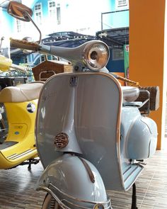 an old scooter is on display in a museum with other motorbikes