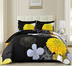 a black and yellow comforter set with flowers on the bed in a white room