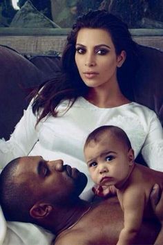 a man and woman laying on top of a couch with a baby in their lap