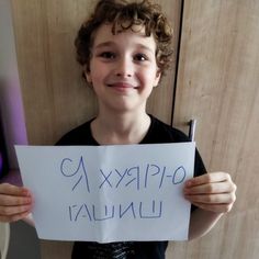 a young boy is holding up a sign