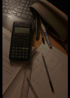 a calculator, pencils, ruler and pen on a desk next to a keyboard