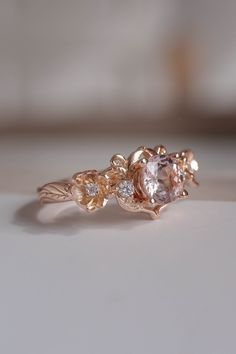 an engagement ring with two different colored stones on it's side, sitting on a white surface