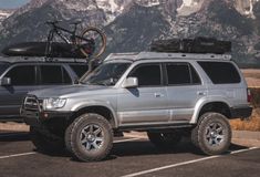 two vehicles parked in a parking lot with mountains in the background