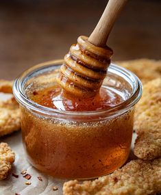 a honey jar with a wooden stick sticking out of it next to some fried food