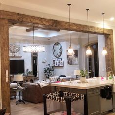 a kitchen and living room are reflected in the mirror on the wall above the bar