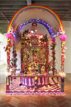 a colorful shrine in the middle of a room with wooden floors and lights on it