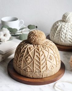 three white knitted hats sitting on top of a table next to yarn and coffee mugs