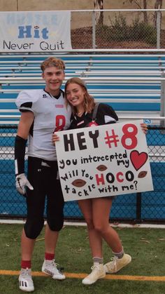 a man and woman standing next to each other holding a sign