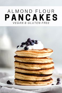 a stack of pancakes with blueberries and whipped cream on top, sitting on a white plate