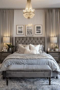 a large bed sitting under a chandelier next to two pictures on the wall