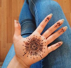 a woman's hand with hendix tattoos on it, sitting on the floor