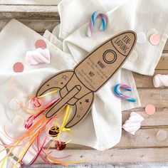 a paper rocket is sitting on top of napkins and confetti streamers