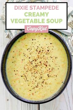 a bowl filled with creamy vegetable soup on top of a white wooden table next to a spoon