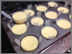 cupcakes with white frosting sitting in a muffin tin on a counter