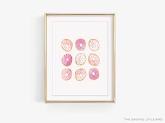 a pink and white donut print with sprinkles on it in a gold frame