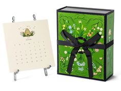 a calendar with a black ribbon tied around it next to a green and white box